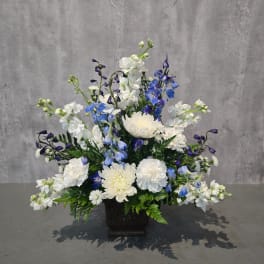 White and blue floral arrangement in a dark square vase