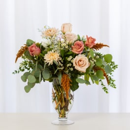 Mixed bouquet of peach and pink roses in a clear glass vase