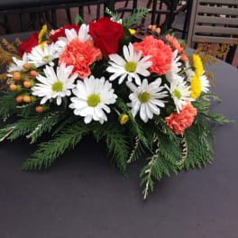 Low floral centerpiece with red roses, white daisies, and coral carnations