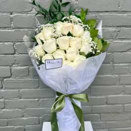 Bouquet of white roses wrapped in white paper with a green ribbon