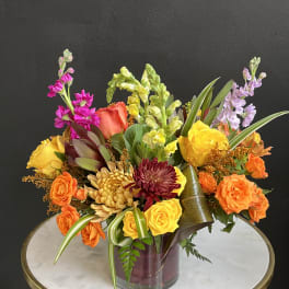 Colorful mixed bouquet in a glass vase with roses and snapdragons