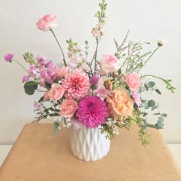 Pink and peach mixed flower arrangement in a white vase