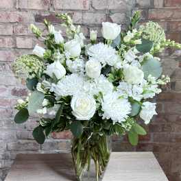 White floral arrangement in a clear glass vase on a table