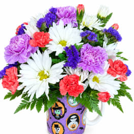Bouquet of daisies, carnations, and purple filler flowers in a Halloween mug