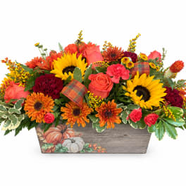 Autumn floral arrangement with sunflowers, roses, and mums in a pumpkin-decorated wooden box