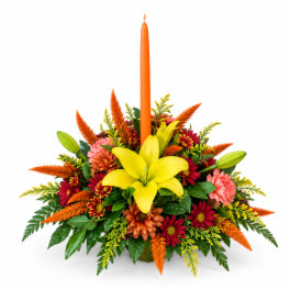 Autumn floral centerpiece with a tall orange candle and yellow lily