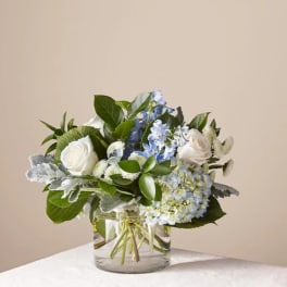 White roses and blue hydrangeas in a clear glass vase