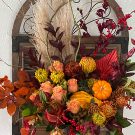 Autumn floral arrangement with roses, mums, and pumpkins in a metal container