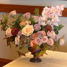 Large bouquet of pastel roses and orchids in a dark vase
