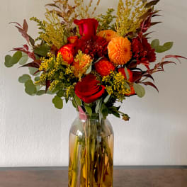 Red and orange flower bouquet in a glass vase