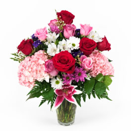 Bouquet of red and pink roses with white daisies in a glass vase