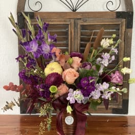 Mixed bouquet in a ribbed vase with purple, peach, and lavender flowers