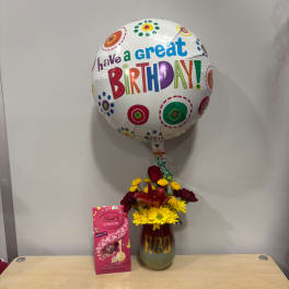 Birthday balloon above a flower vase and a box of chocolates