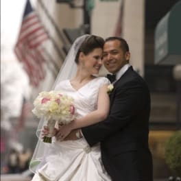 Bride and groom posing with a white and pink bouquet