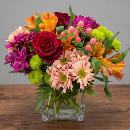 Mixed bouquet of roses, daisies, and alstroemeria in a clear glass vase