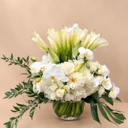 White calla lilies, orchids, and roses arranged in a glass vase