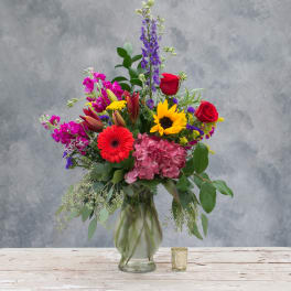 Mixed bouquet in a glass vase with roses, lilies, hydrangea, and a sunflower