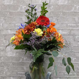 Mixed bouquet in a glass vase with red, orange, yellow, and purple flowers