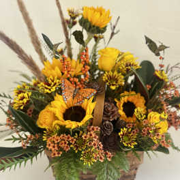 Autumn flower basket with sunflowers, yellow roses, and an orange butterfly accent