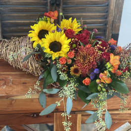 Mixed bouquet with sunflowers, roses, and chrysanthemums in a woven wrap