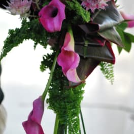 Bouquet of pink and purple calla lilies with green foliage