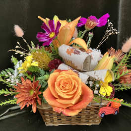 Basket arrangement with orange roses, lilies, and mixed fall flowers