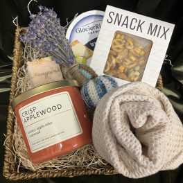Gift basket with a candle, snack mix, soap, and a rolled knit item