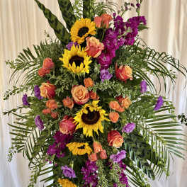 Tall standing floral spray with sunflowers, roses, and purple blooms