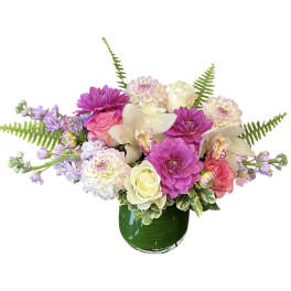 Mixed pink, white, and lavender flowers in a green glass vase