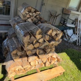 Stacked firewood bundles wrapped in plastic on a porch
