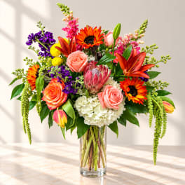 Colorful mixed bouquet in a clear glass vase with roses and lilies