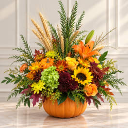 Fall floral arrangement in a pumpkin container with sunflowers and lilies