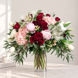 Mixed bouquet of red, pink, and white flowers in a clear glass vase