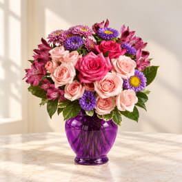 Pink and purple flower bouquet in a purple glass vase