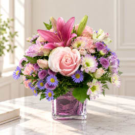 Pink and purple mixed bouquet in a square glass vase
