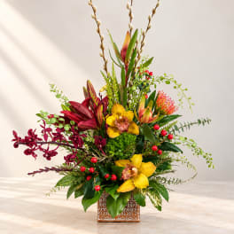 Tall tropical flower arrangement in a patterned square vase