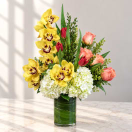 Yellow orchids and pink roses in a glass vase with white hydrangeas
