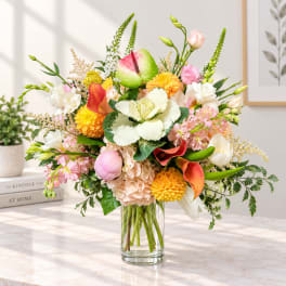 Mixed bouquet in a clear glass vase with pink, white, yellow, and orange blooms
