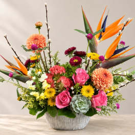 Colorful mixed flower arrangement in a white textured bowl vase