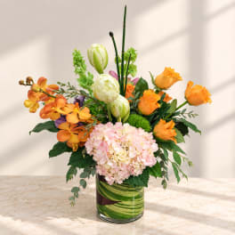 Orange roses and pink hydrangeas in a glass vase