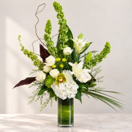 Tall white and green floral arrangement in a glass vase