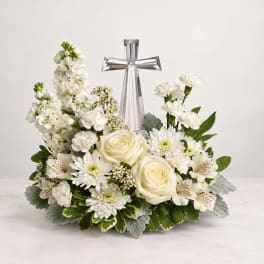 White floral arrangement with roses, daisies, and a clear crystal cross