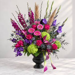 Bright mixed bouquet in a black urn vase with pink, purple, and green blooms