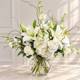 White lilies and roses arranged in a clear glass vase