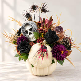 Halloween floral arrangement in a white pumpkin with a skull accent
