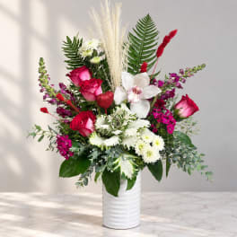 Pink and white mixed bouquet in a white vase with tall grasses