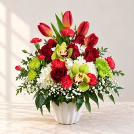 Mixed bouquet of red roses, tulips, orchids, and white hydrangeas in a white vase