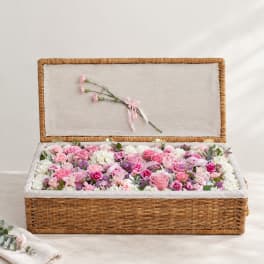 Pink and white floral arrangement in an open wicker basket