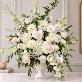 White and blush floral arrangement in a white urn vase