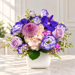 Purple and pink flower arrangement in a white vase
